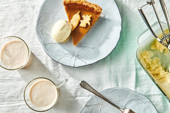Slice of pumpkin pie and scoop of ice cream on a plate.