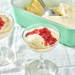 Long-stemmed glasses of ice cream topped with strawberry sauce.