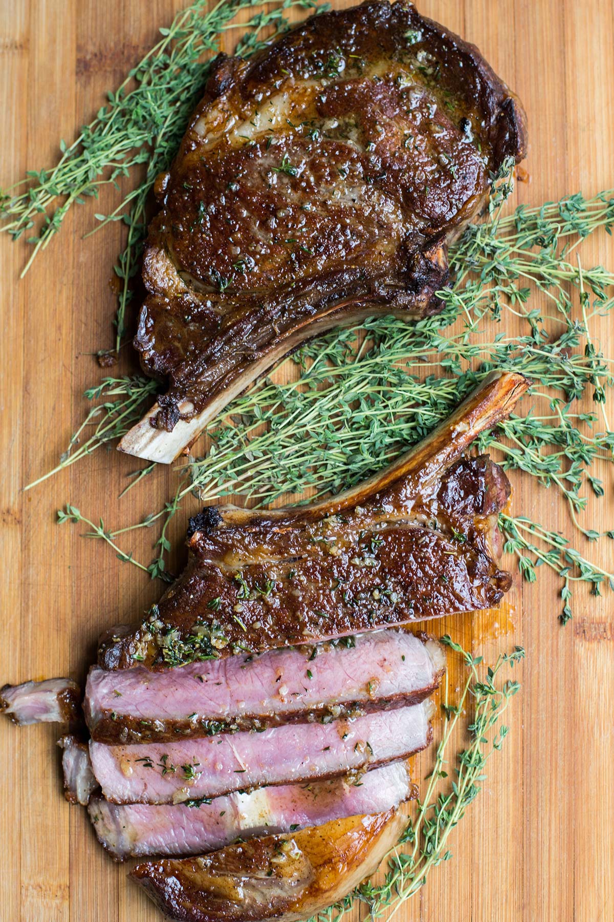 Ribeye and fresh thyme on cutting board.