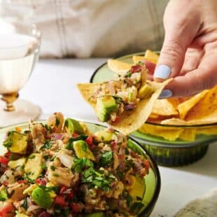 Woman holding a tortilla chip loaded with Shrimp Ceviche.