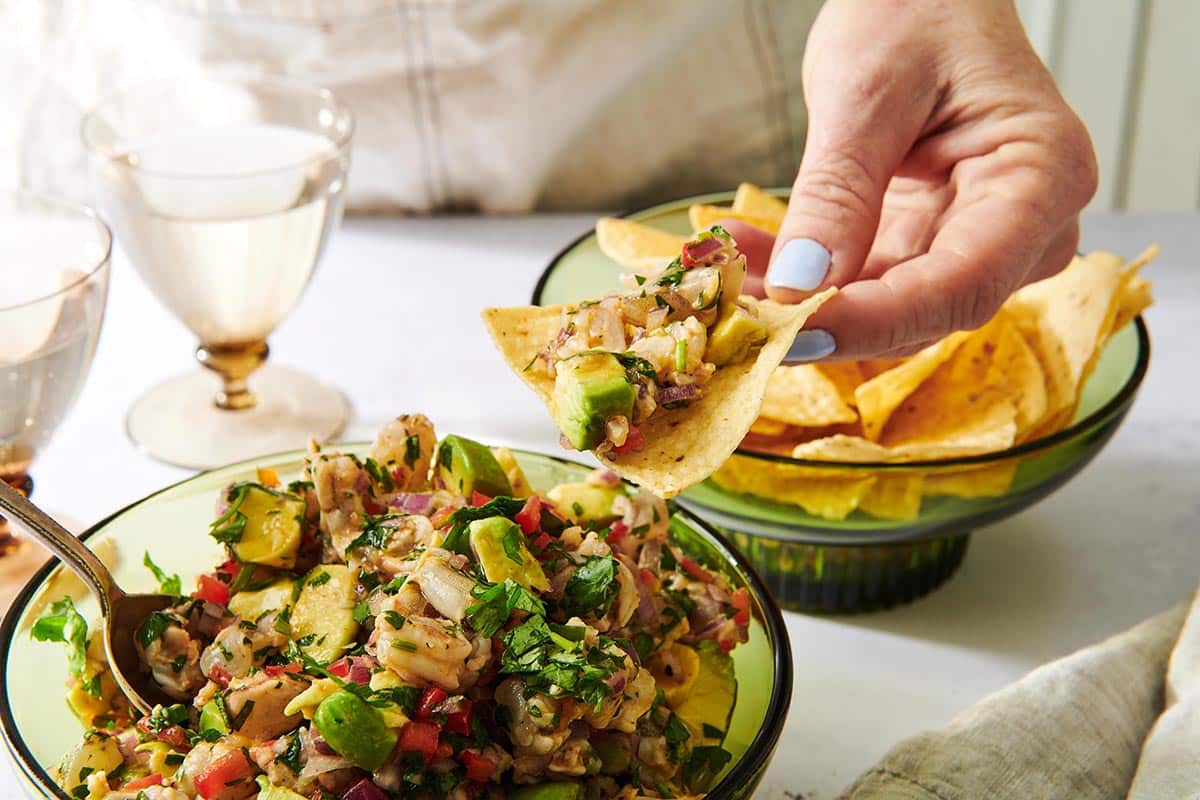 Woman holding a tortilla chip loaded with Shrimp Ceviche.