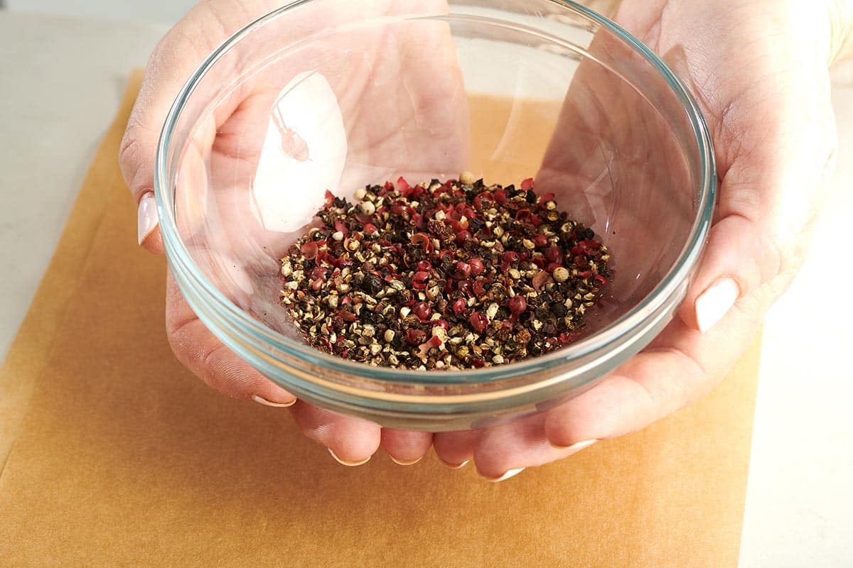 Woman holding a small glass bowl of multi-colored pepper.