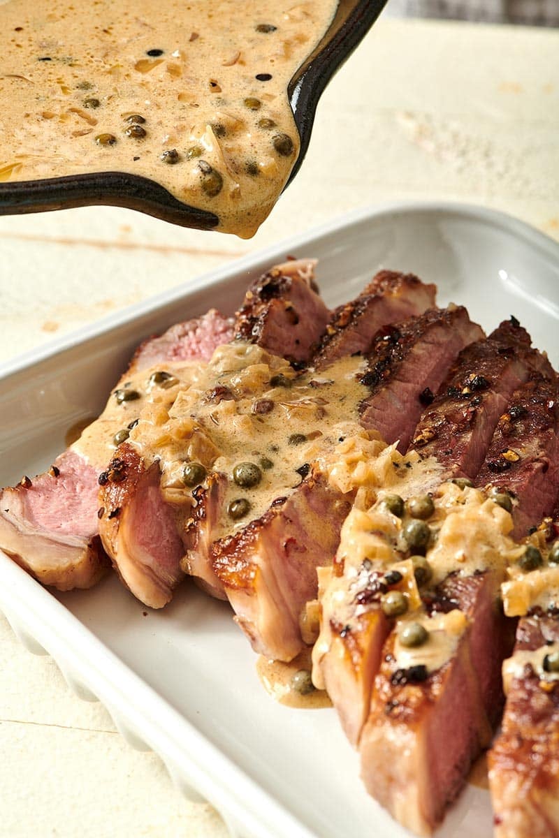 Sauce pouring over sliced steak.
