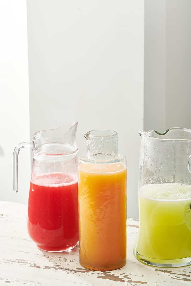 Pitchers of red, orange, and green Agua Fresca.