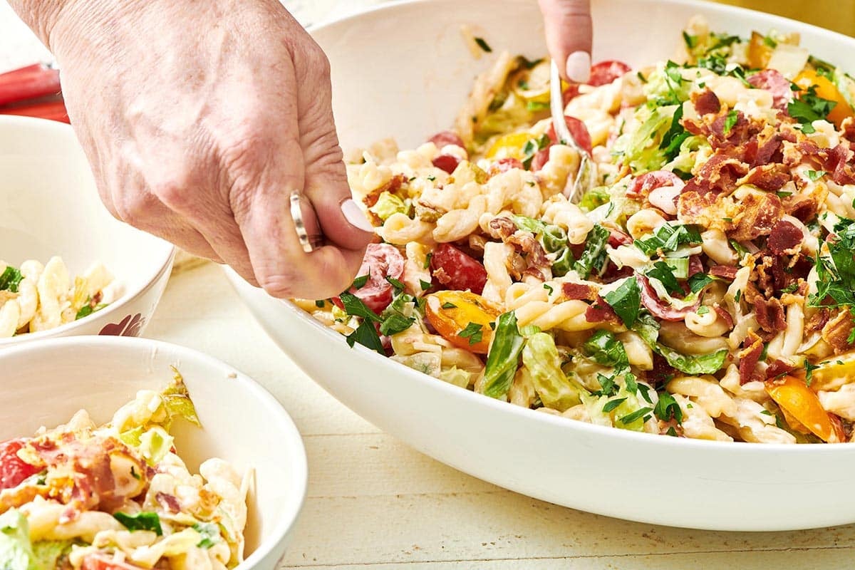 Serving BLT pasta salad with large spoons.