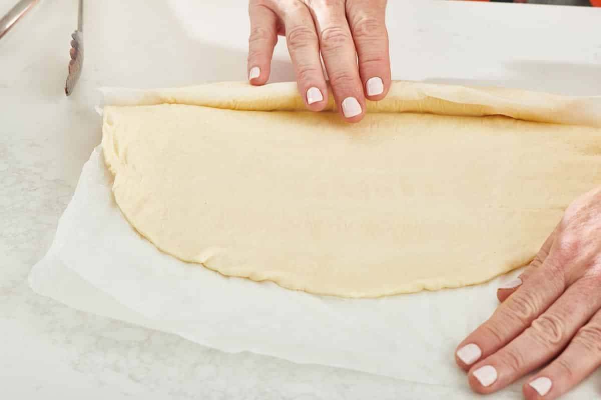 Woman unrolling pizza dough.