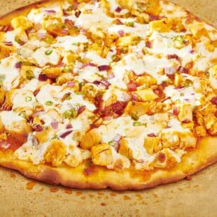 Unsliced Buffalo Chicken Pizza on parchment paper.