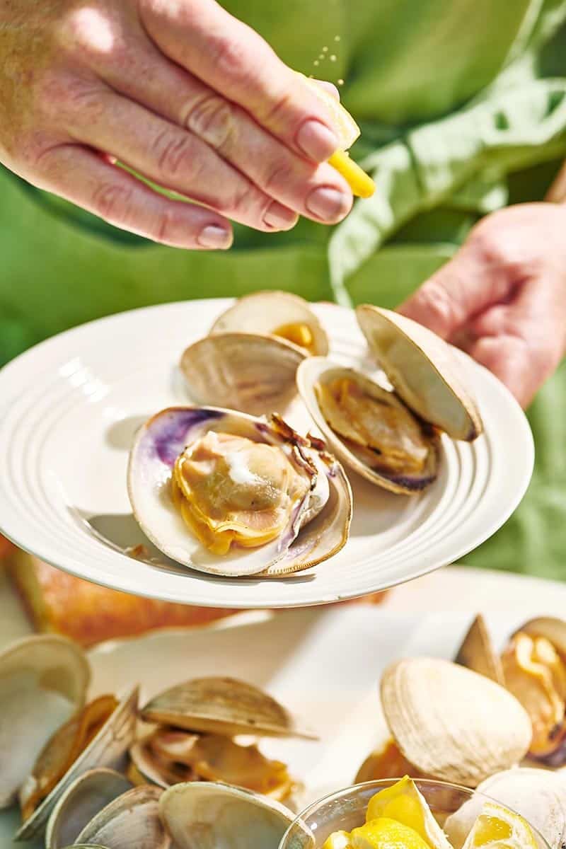 Woman squeezing lemon juice onto Grilled Clams.