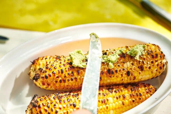 Knife putting jalapeno butter on Grilled Corn on the Cob.