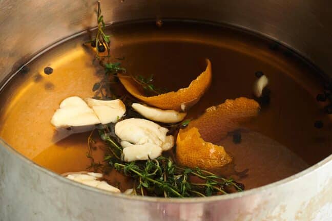 Pot of brine with orange peels, thyme, and garlic.