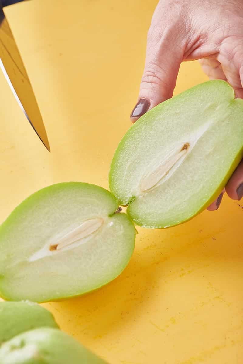 Woman cutting a fresh chayote in half