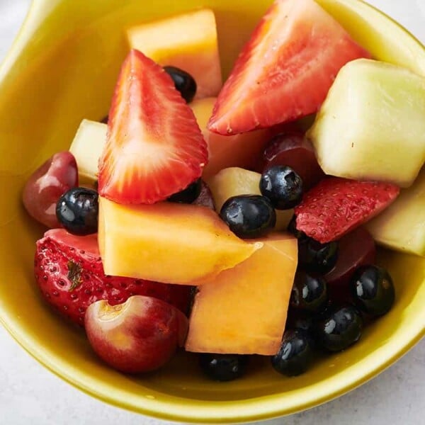 Mixed fruit salad in small yellow bowl.