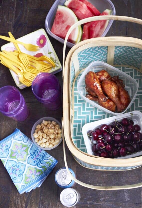 Chicken, cherries, and popcorn in plastic containers with a basket.