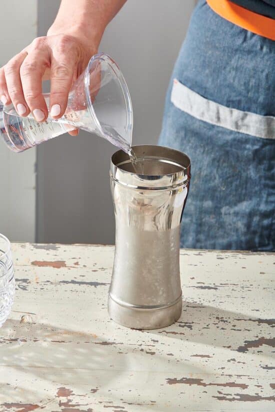 Woman pouring pisco into a cocktail shaker.