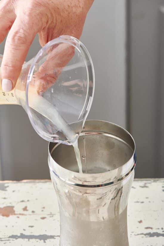 Lime juice being poured into a cocktail shaker.