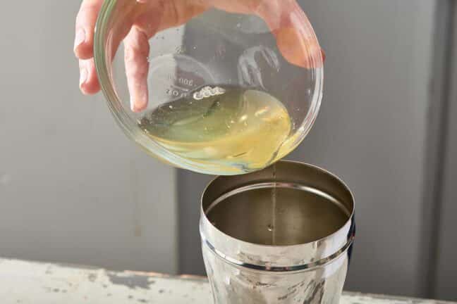 Bowl of egg white being poured into a cocktail shaker.