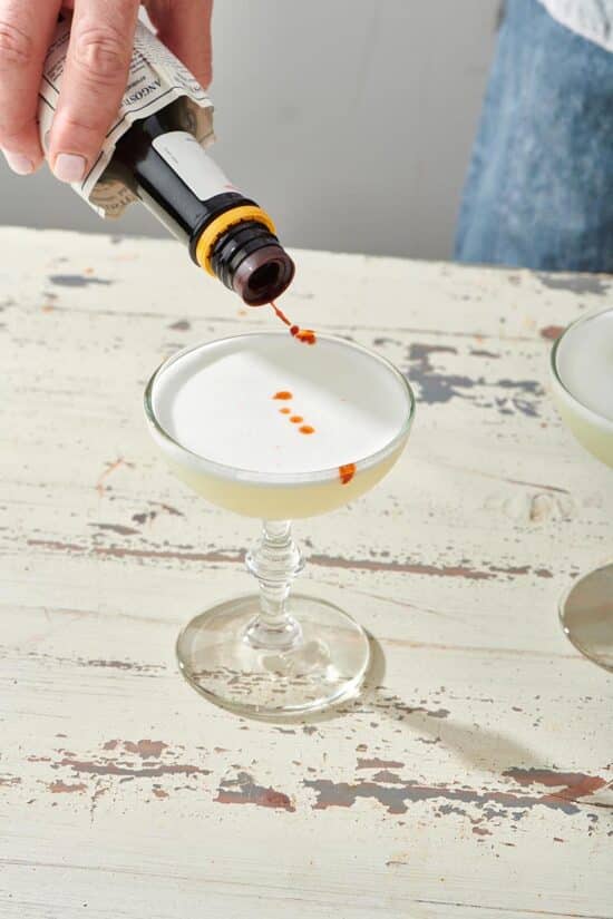 Pisco Sour being topped with bitters.