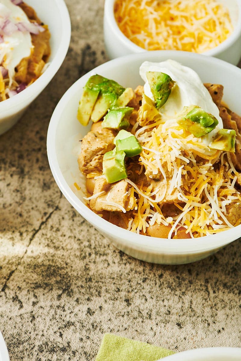 White Chicken Chili topped with avocado, sour cream, and shredded cheese.