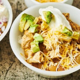 White Chicken Chili in white bowl with toppings.