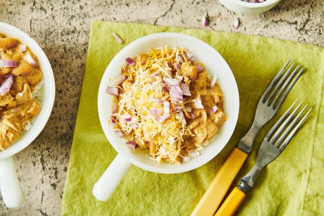 Bowl of White Chicken Chili topped with shredded cheese and red onion.
