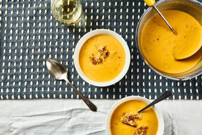 Two bowls and a pot of Pumpkin Curry Soup.