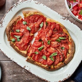 Partially-sliced Tomato Pie Pizza on a serving platter.
