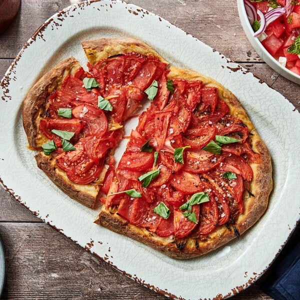 Partially-sliced Tomato Pie Pizza on a serving platter.