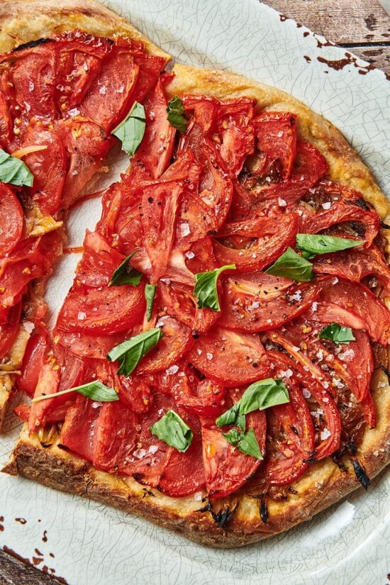 Tomato Pie Pizza sliced in half and on a plate.