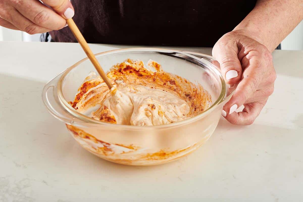 Woman using a wooden spoon to stir Chipotle Mayo.