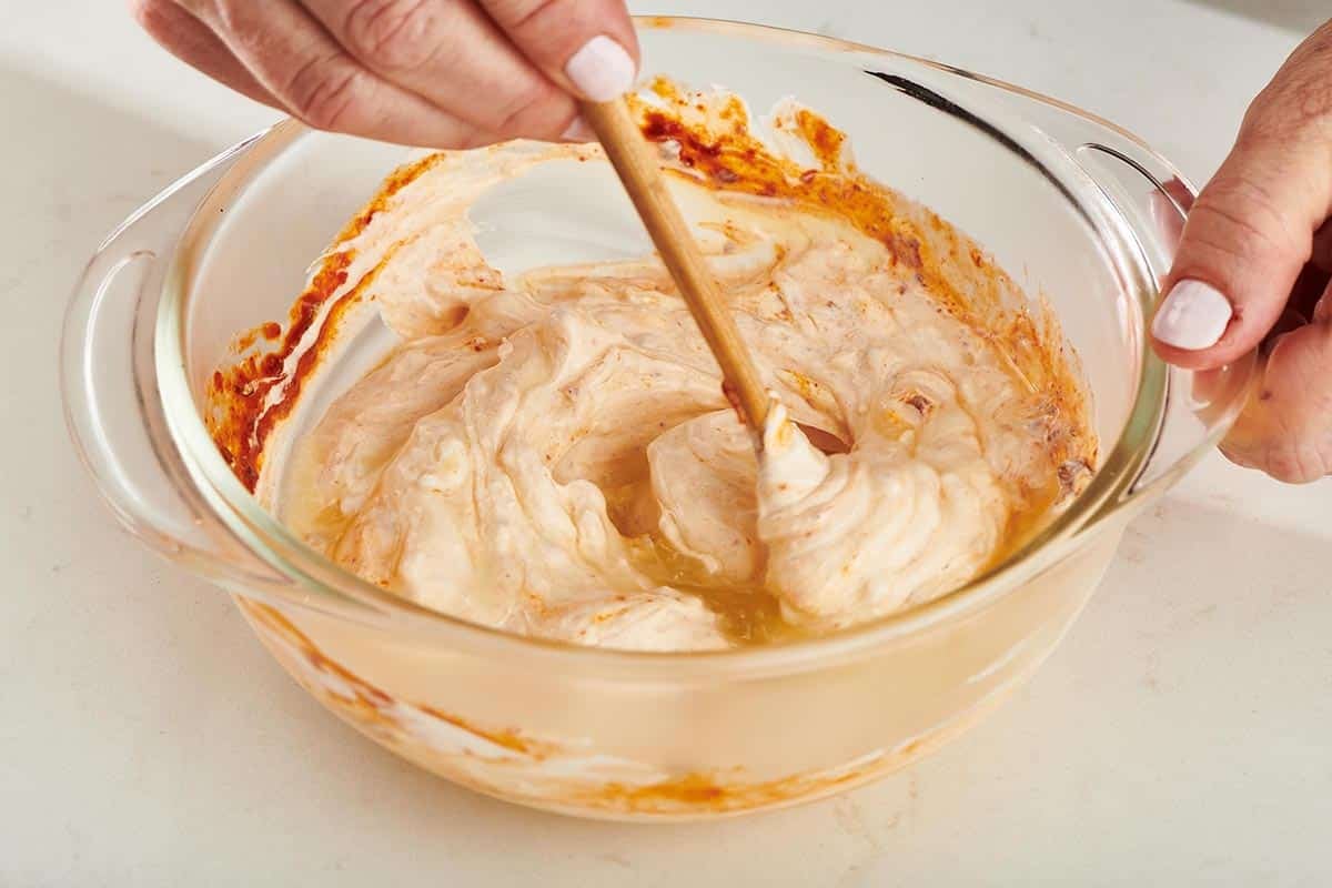 Mixing spicy mayonnaise in bowl with spoon.