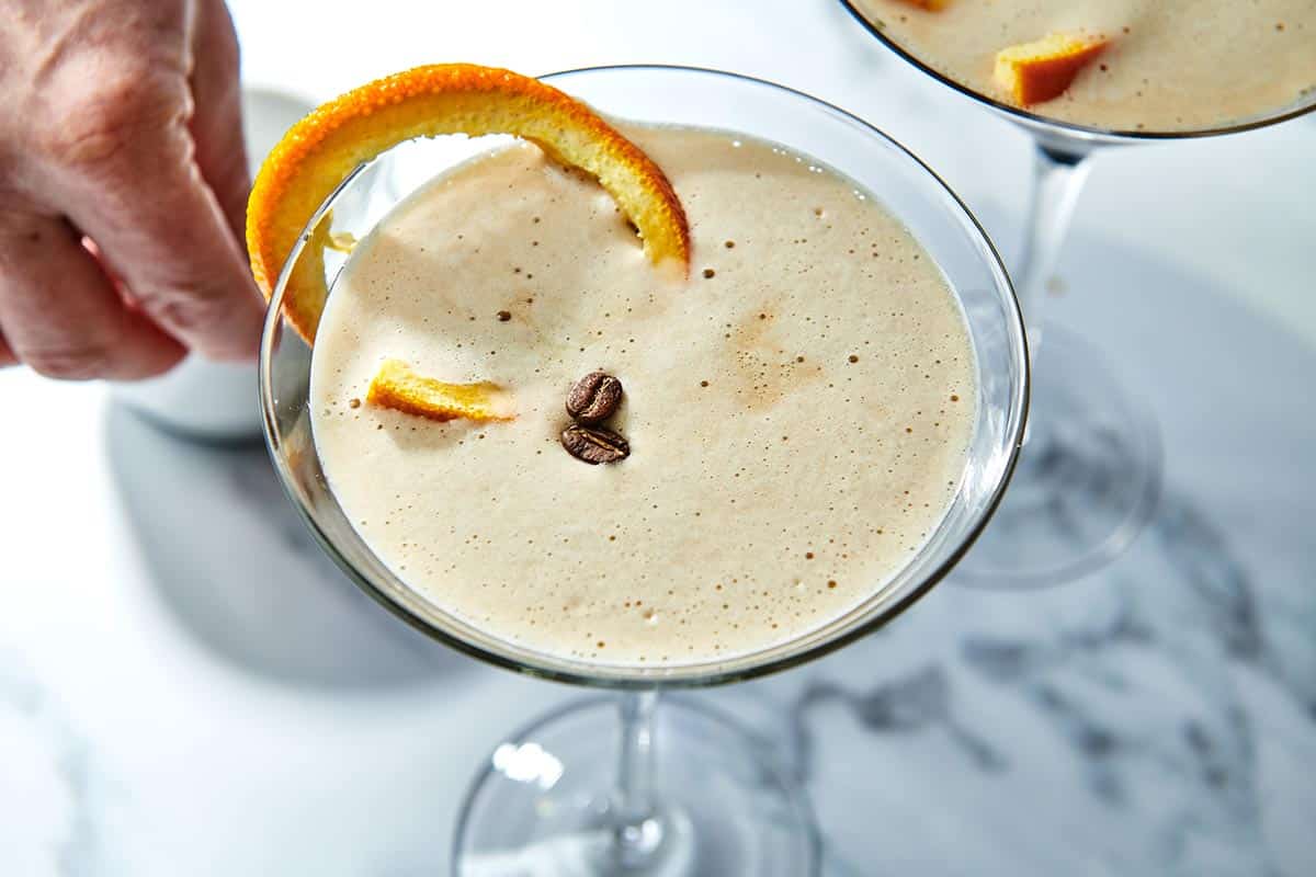 Espresso Martini topped with coffee beans and a slice of orange rind.