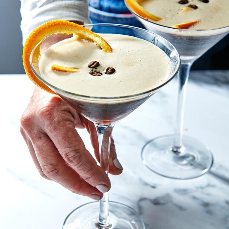 Woman grabbing an Espresso Martini in a long-stemmed glass.