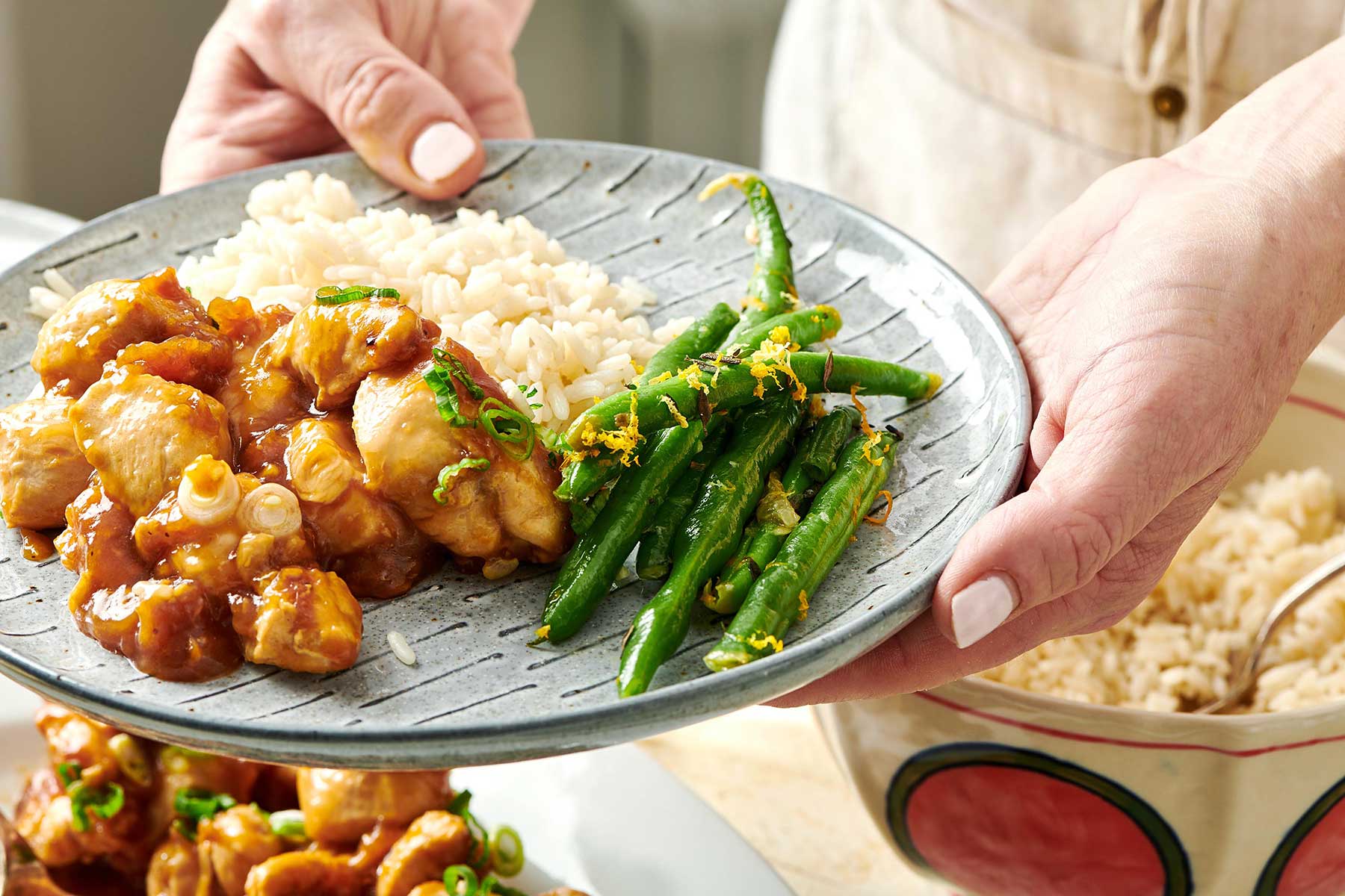 Green Beans with Gremolata on a plate with orange chicken.