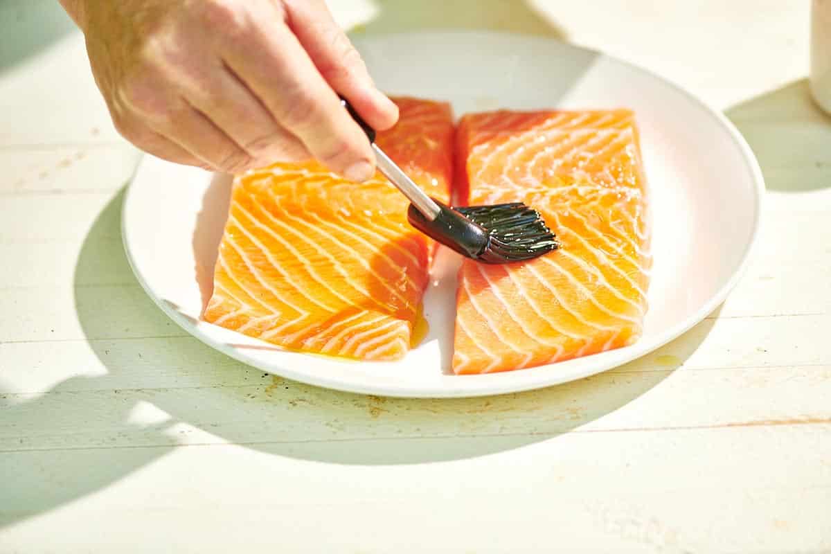 Brushing oil on raw salmon filets.