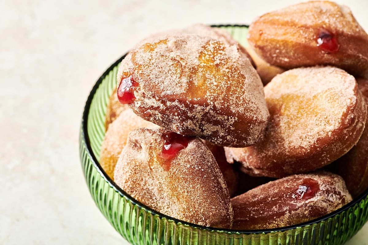 Pile of Jelly Doughnuts in a green bowl.