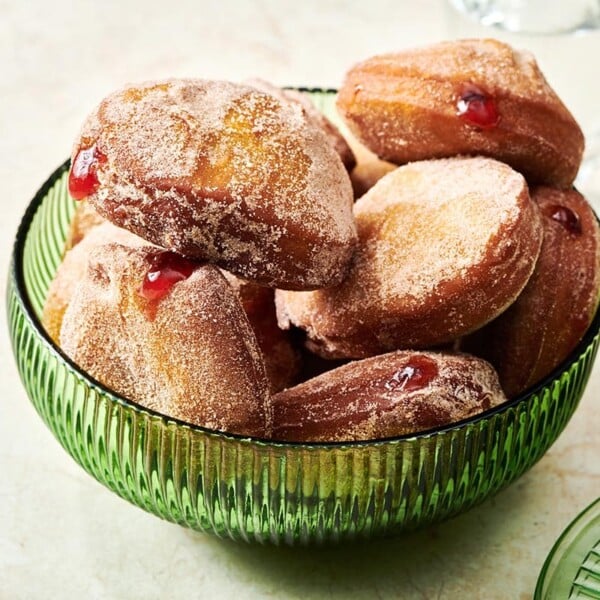 Pile of Jelly Doughnuts in a green bowl.