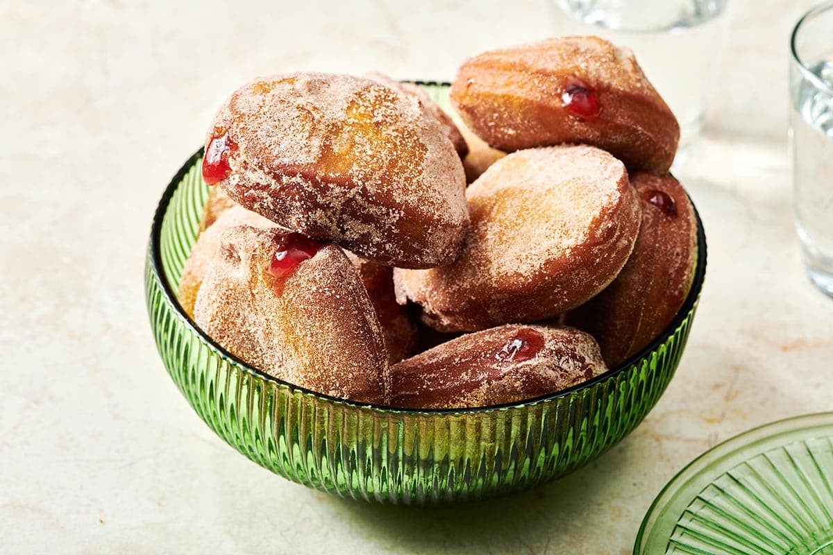 Pile of Jelly Doughnuts in a green bowl.