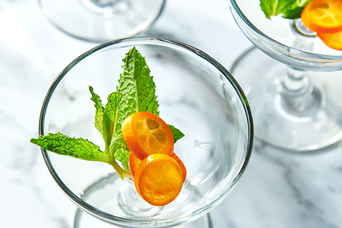 Fresh mint and kumquat in cocktail glass.