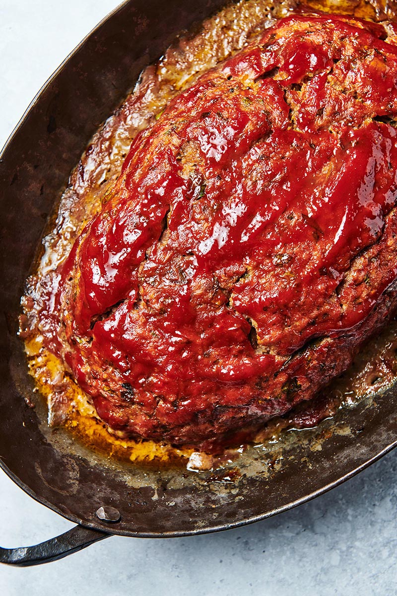Cooked Meatloaf in a pan topped with ketchup.