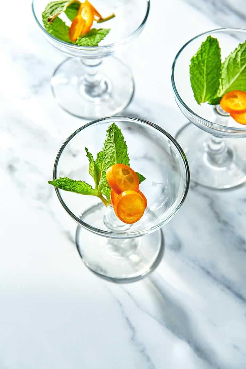 Fresh mint and kumquat in cocktail glass.