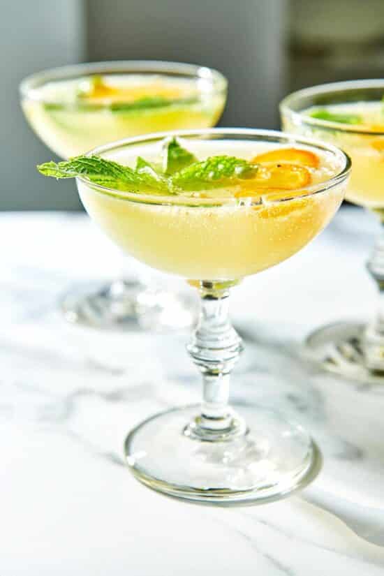 Long-stemmed glasses filled with Kumquat Mint Cocktail.