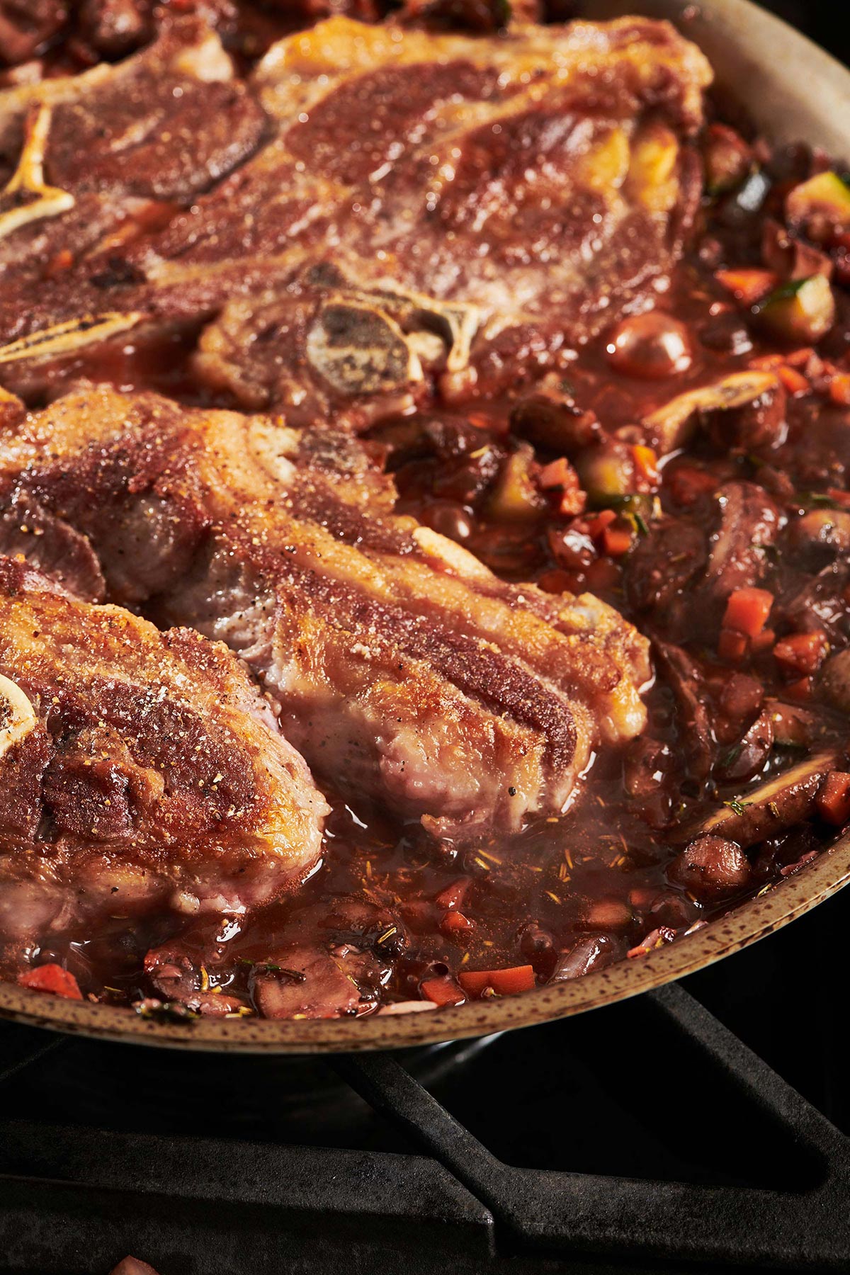 Braised Lamb Shoulder Chops in a pan on the stovetop.