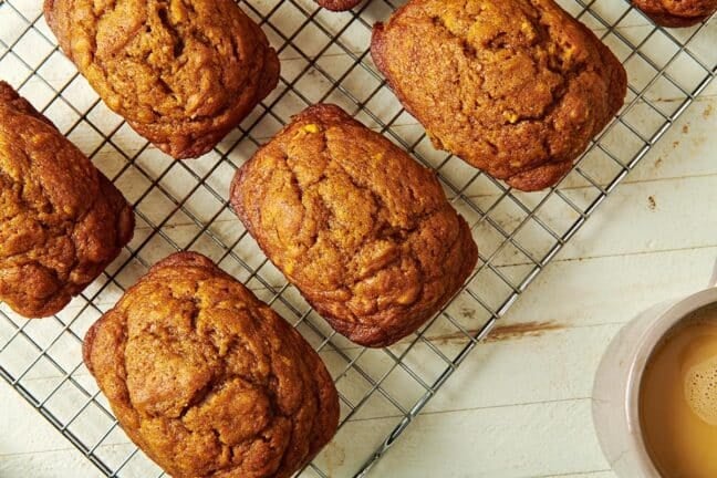 Mini Pumpkin Bread Loaves on a wire rack set on a wooden table.