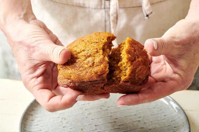 Woman pulling apart a mini pumpkin bread loaf.