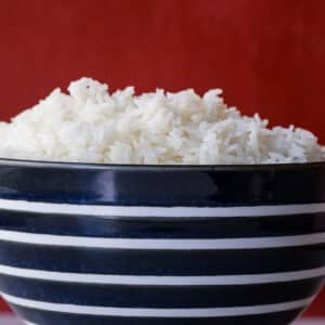 Fluffy cooked white rice in a blue and white striped bowl.