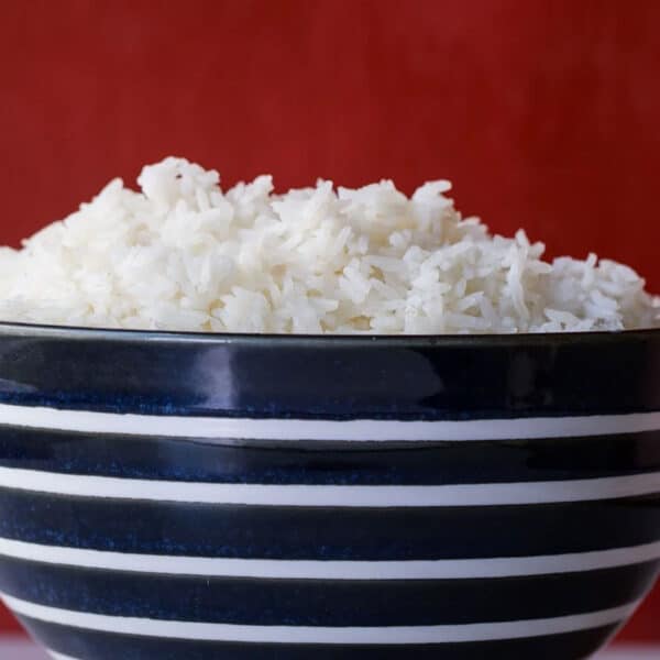 Fluffy cooked white rice in a blue and white striped bowl.