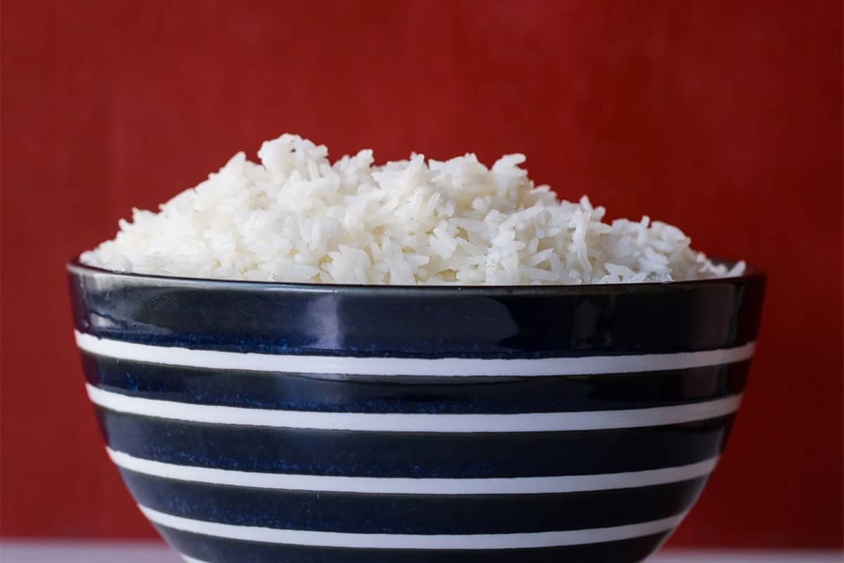 Fluffy cooked white rice in a blue and white striped bowl.