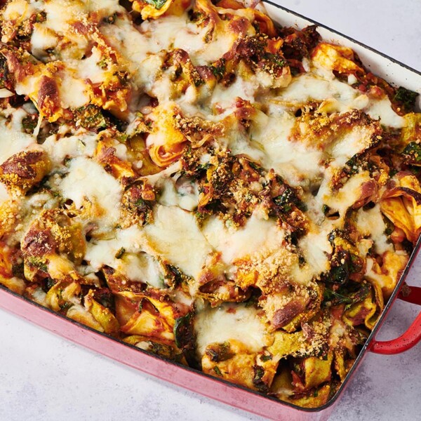 Baked Tortellini in a red, handled baking dish.
