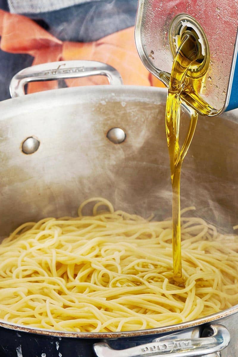 Olive oil pouring onto a pot of noddles.