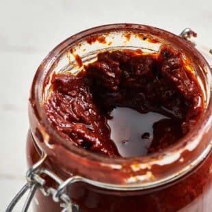 Harissa Sauce in a jar with the lid off.